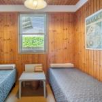 Two beds in a room with wood paneling and a window. An old map hangs on the wall.