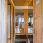 Wood-paneled entryway with view into kitchen and living area.
