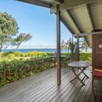 Deck with table and chair, view of water and trees.