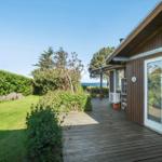 Wooden deck with view of green areas and sea. Entrance door and outdoor area visible.