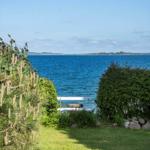 Green garden with view of the blue sea and a white wooden chair.