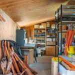 Wood-paneled garage with shelves, tools, and boxes.