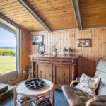 Room with wooden walls and ceiling, seating, table, and window with view of water.