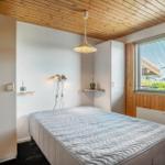 Bedroom with bed, wooden ceiling, and window with blinds.