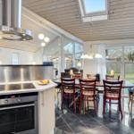 Kitchen with dining area, black tiles, wooden ceiling, and large window.