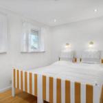 Bedroom with double bed, two windows, and wooden floor.