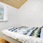 A bedroom with bed, window, and wooden ceiling.