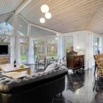 Large living and dining area with black floor, wooden ceiling, and ample windows.