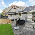 Backyard with hot tub, seating under umbrella, and grill. Lawn and paved patio area.