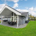 A house with terrace, garden, and outdoor seating under a blue sky.