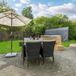 Terrace with seating, umbrella, and hot tub in the background.