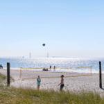 Beach with volleyball net and view of the Oresund Bridge.