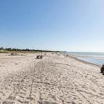 Beach with sand, people, and sea under blue sky
