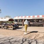 Coffee and ice cream stand with seating and ice cream sculpture outdoors.