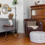 Living room with gray sofa, brown leather armchair, and wooden floor.