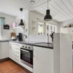 Kitchen with white cabinets, dark countertop, and windows with view of nature.