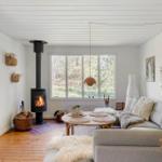 Living room with fireplace, sofa, and hardwood floor. Large windows and wall decor.