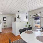 Dining area with round table and black chairs. Kitchen and living area are visible.