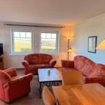 Wohnzimmer mit rotem Sofa, Fernseher und Blick auf Felder.