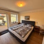 Schlafzimmer mit Doppelbett, Fenster und Glastür zum Garten.