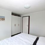 Schlafzimmer mit Bett, Schrank und Wandbild. Deckenleuchte und Nachttischlampe.