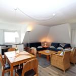 Wohn- und Essbereich mit Küchenzeile, Sofa und Esstisch mit Stühlen.