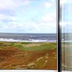 Blick auf das Meer und Küstenlandschaft durch ein Fenster.