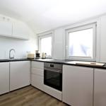 Küche mit weißen Schränken, schwarzer Arbeitsplatte und Fenster.