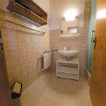 Badezimmer mit Waschbecken, Spiegel, Heizkörper und Dusche.