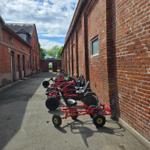 Rote Go-Karts stehen in einer Straße zwischen Backsteinhäusern.