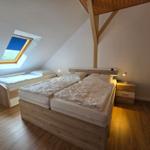 Schlafzimmer mit Doppelbett, kleinem Bett und Dachfenster.