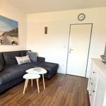 Wohnzimmer mit Sofa, Tisch, Fernseher und Wandbild