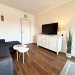 Wohnzimmer mit Sofa, TV-Schrank und Holzboden
