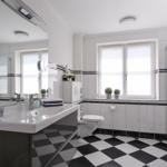 Badezimmer mit Waschbecken, Toilette und Dusche. Schwarze und weiße Fliesen.