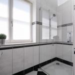 Badezimmer mit Dusche, Fenster und zwei Pflanzen auf der Fensterbank.