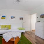Wohnzimmer mit weißem Sofa, grünem Teppich und Holzboden.