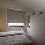 Zimmer mit zwei Betten, Fenster und Wandspiegel.