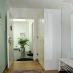 Flur mit Holzboden, Spiegelschrank und Pflanze im Hintergrund.