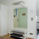 Eingangsbereich mit Spiegelschrank, Kleiderständer und Garderobe. Blick in die Badewanne mit Fliesenboden.