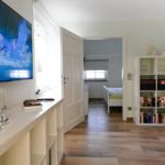 Wohnzimmer mit TV, Bücherregal und Blick in Schlafzimmer mit Bett.