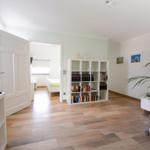 Wohnzimmer mit Bücherregal, Sofa und Blick in Schlafzimmer