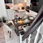 Essbereich mit Tisch, Stühlen und Küchenbereich im Hintergrund.