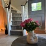 Haus mit Treppe, Eingangstür und Blumen auf Tisch