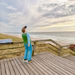 Statue eines Mannes mit Fernglas auf Holzterrasse am Strand