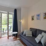 Ein Wohnzimmer mit Sofa, Bildern und Terrassentür. Blick auf Garten.