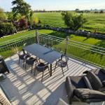 Terrasse mit Tisch, Stühlen und Liegen. Blick auf grüne Wiesen und Bäume.