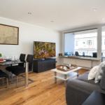 Wohnzimmer mit Essbereich, TV und Balkon. Holzboden und moderne Möbel.