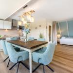 Küche mit Esstisch und Schlafzimmer im Hintergrund.