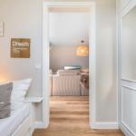 Schlafzimmer mit Blick in Wohnbereich mit Sofa und Deckenlicht.