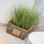 Badezimmer mit Korb, Gras und Mosaikfliesen.